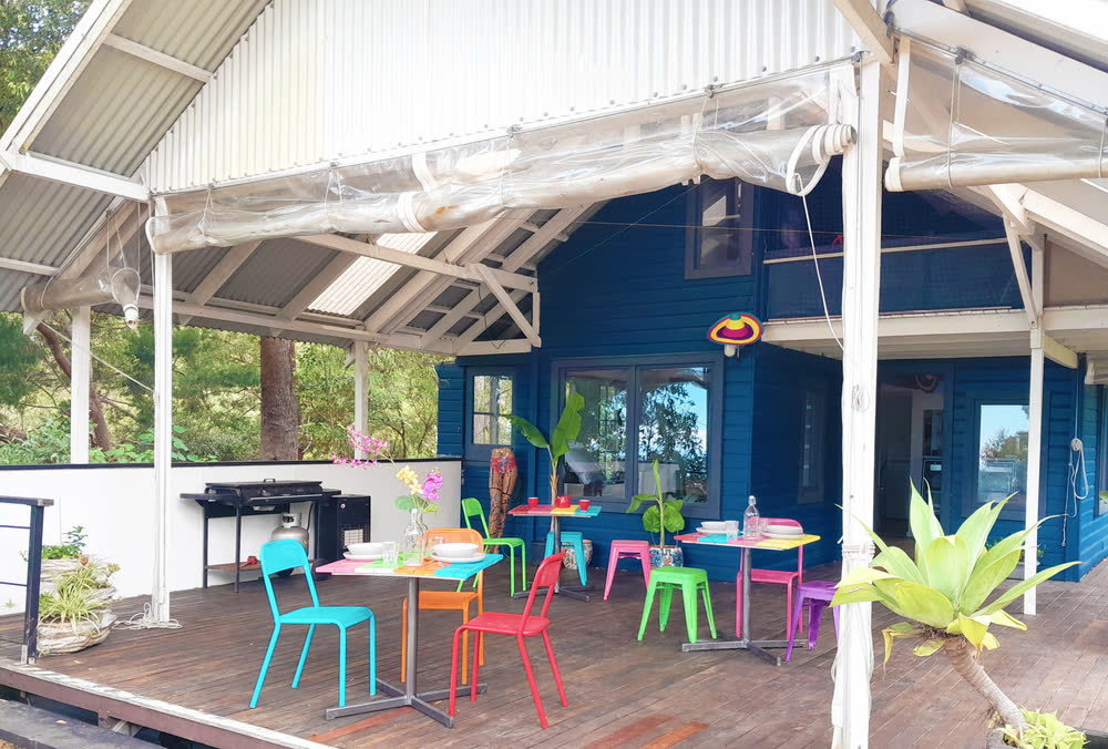 The covered guest lounge with brightly coloured tables and chairs